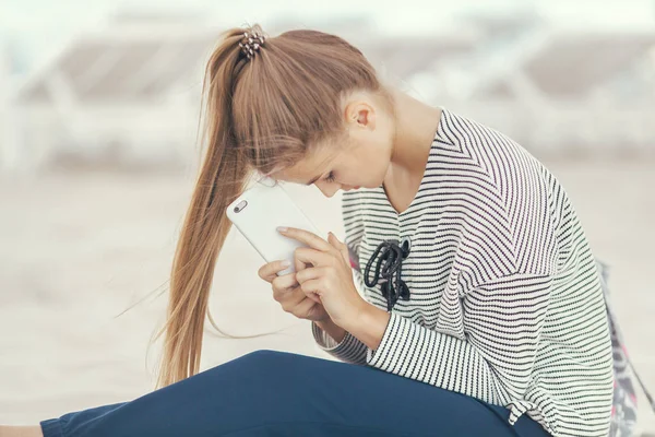 Žena se smartphonem na pláži. Dovolená a technika. — Stock fotografie