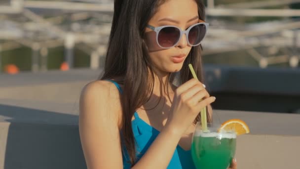 Unga asiatiska mode kvinna dricka cocktail på en strandbar. — Stockvideo