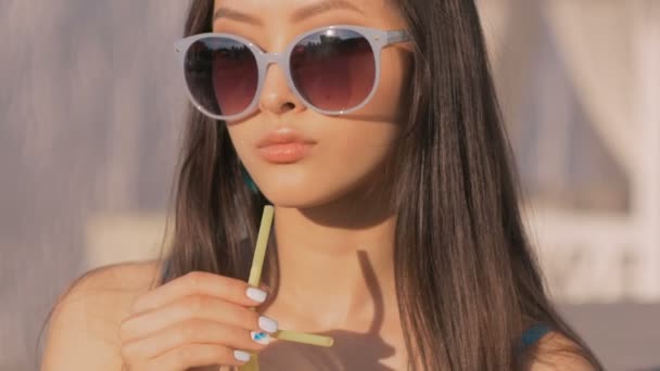 Jeune femme de mode asiatique boire un cocktail dans un bar de plage . — Video