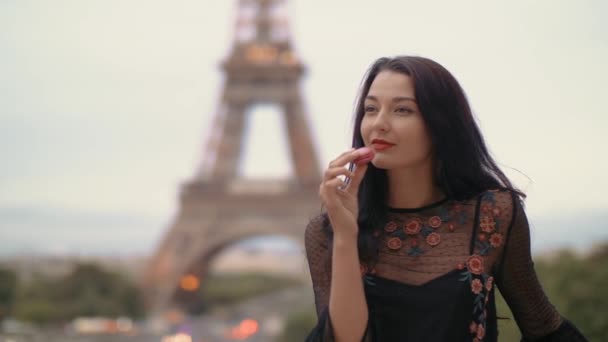 Mujer de París sonriendo comiendo la pastelería francesa macaron en París contra la torre Eiffel. — Vídeo de stock