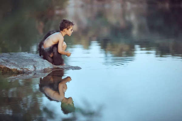 Cavernícola. Niño sentado en la playa y mirando el agua —  Fotos de Stock