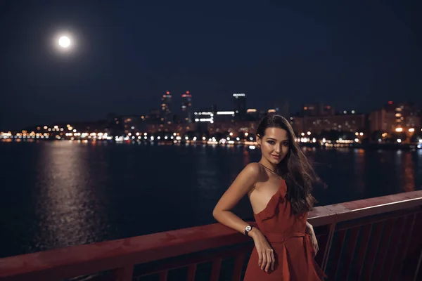 Young ellegant woman standing on the ligths of the night city background. Freedom and girl in love concept