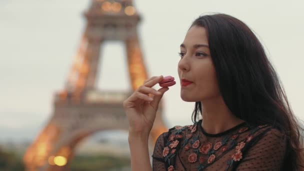Mujer de París sonriendo comiendo la pastelería francesa macaron en París contra la torre Eiffel. — Vídeo de stock