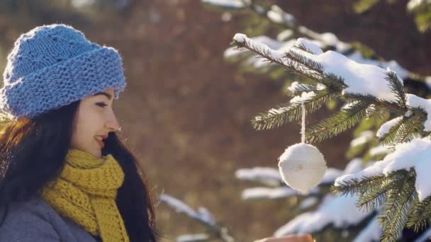 Vrouw versiert fir-tree met speelgoed tijdens Nieuwjaar in bos — Stockvideo