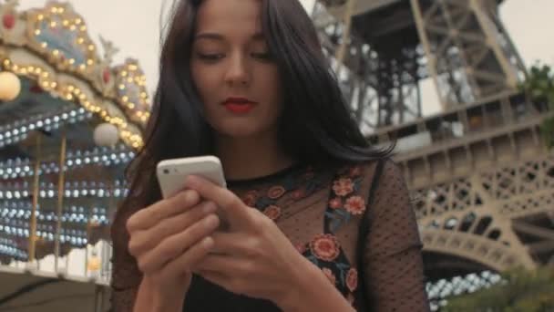 Za pomocą smartfonu, patrząc na mapę, w pobliżu wieży Eiffla i karuzela, Kobieta podróż Paryż. — Wideo stockowe