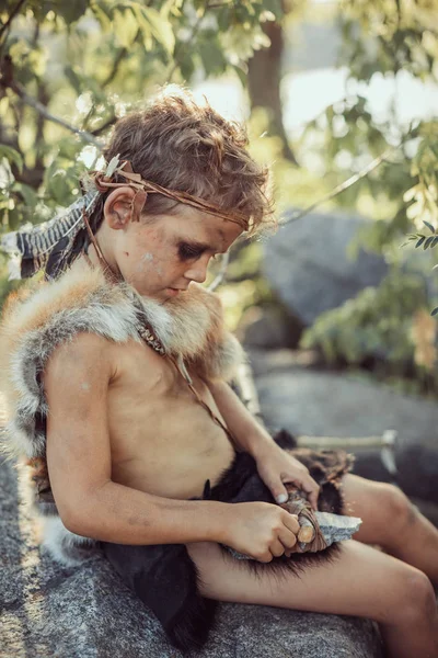 Cavernícola, chico varonil haciendo arma de piedra primitiva en el campamento — Foto de Stock