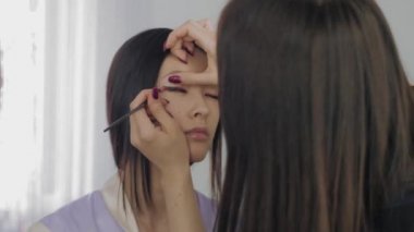 Genç Asyalı modelleri yüz makyaj işlemi sırasında.