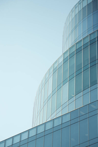 Business abstract - modern office building covered with glass against blue sky. Copy space. Details of architecture