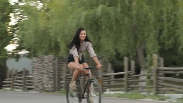 Mujer joven montando una bicicleta al aire libre — Vídeos de Stock