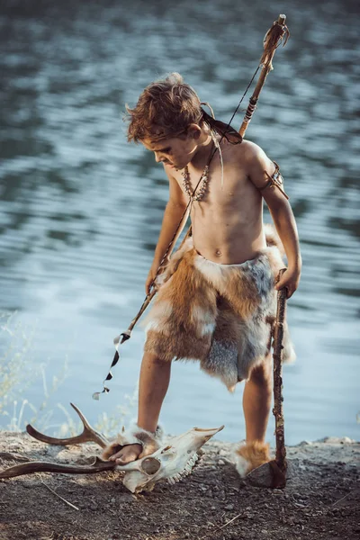 Hombre de las cavernas enojado, chico varonil con armas primitivas antiguas cazando al aire libre. Antiguo guerrero prehistórico. Mirada de película heroica —  Fotos de Stock