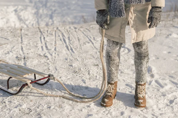 Winterstiefel auf Schnee in der Nähe von Schlitten mit Seil. — Stockfoto