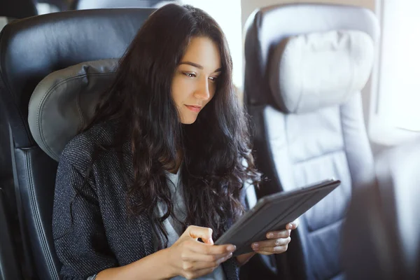 Mujer joven usando su tableta mientras viaja en tren. Concepto de aplicación viaje — Foto de Stock