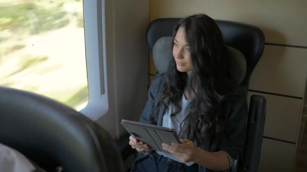 Young woman using her tablet computer while traveling by train. Travel application concept — Stock Video