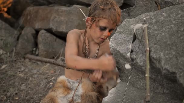 Homme des cavernes, garçon viril faisant une arme de pierre primitive dans le camp — Video