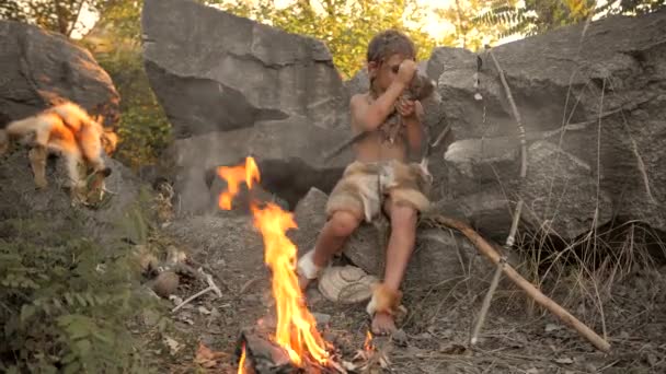 Holbewoner, manly jongen maken van primitieve stenen wapen in kamp — Stockvideo