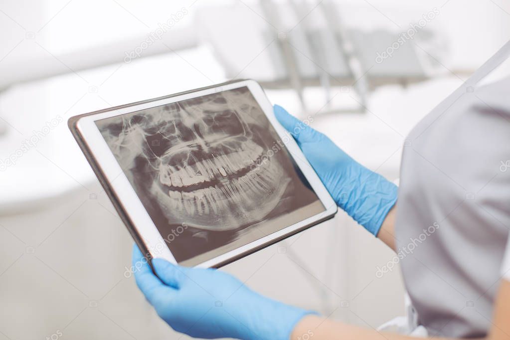 Dentist doctor using digital tablet against dental equipment.