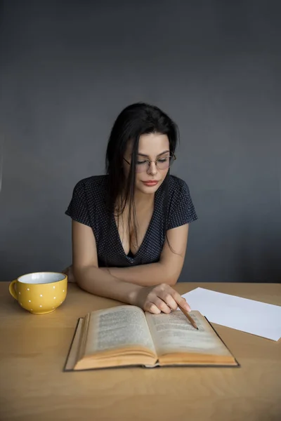 Beautiful young woman in glasses reading a book. — Stock Photo, Image