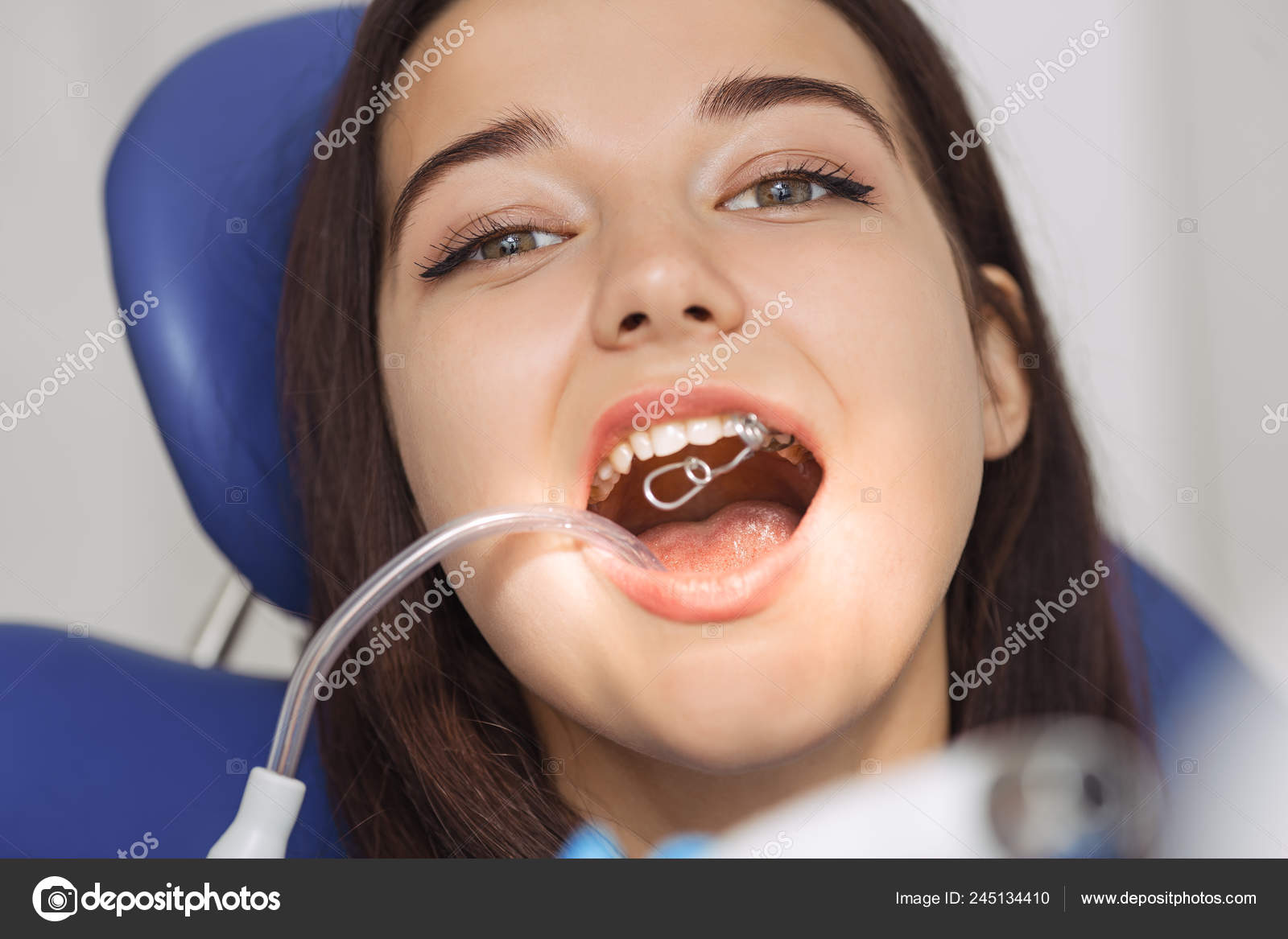Dentist doing a dental treatment on a female patient. Stock Photo by