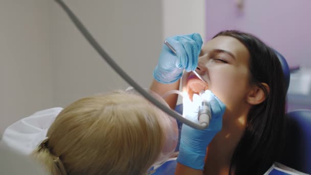 Dentista fazendo um tratamento odontológico em uma paciente do sexo feminino. — Vídeo de Stock