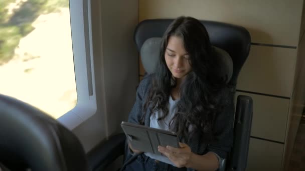 Jonge vrouw met behulp van haar tablet-pc terwijl het reizen met de trein. Reizen toepassing concept — Stockvideo