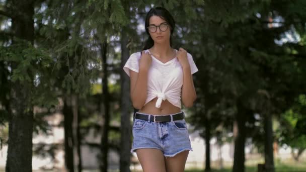Młoda kobieta samotnie z plecaka stojący samotnie w parku. Hipster dziewczyna w słonecznym lesie — Wideo stockowe