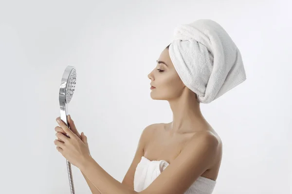 Jovem mulher em uma toalha segurando cabeça de chuveiro — Fotografia de Stock