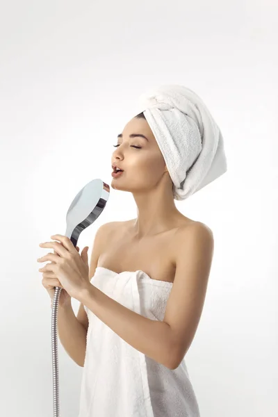 Mladá žena v ručník drží sprchová hlava — Stock fotografie