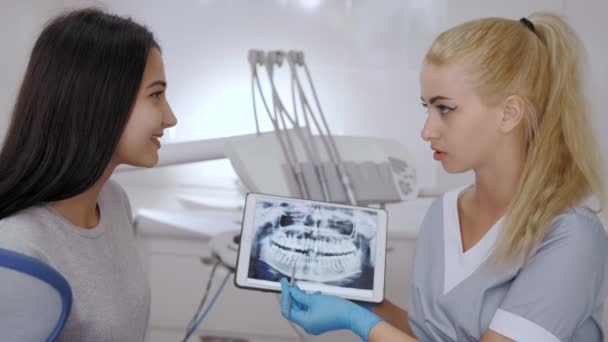 Tandläkare och patient väljer behandling i samråd med medicinsk utrustning i bakgrunden — Stockvideo