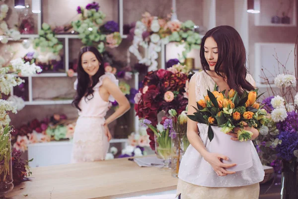 Belle donne asiatiche fioristi felici di lavoro nel negozio di fiori con un sacco di fiori primaverili — Foto Stock