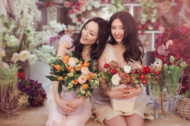Beautiful asian women florists with bouquet of flowers in flower store clipart