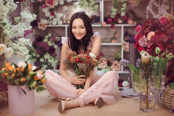 Bella donna asiatica fiorista in abito rosa con mazzo di fiori in mano nel negozio di fiori — Foto Stock