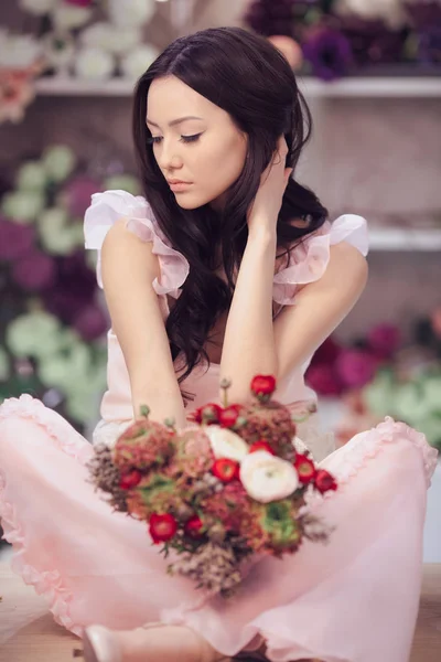 Hermosa mujer asiática florista en vestido rosa con ramo de flores en las manos en la tienda de flores — Foto de Stock