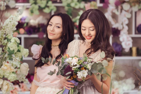 Женщины-флористы счастливы работать в цветочном магазине с большим количеством весенних цветов — стоковое фото