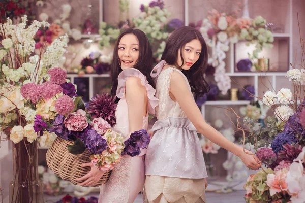 Belle donne asiatiche fioristi felici di lavoro nel negozio di fiori con un sacco di fiori primaverili — Foto Stock