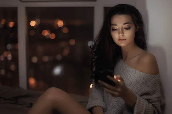 Wanita menggunakan ponsel di dalam ruangan pada malam hari — Stok Foto