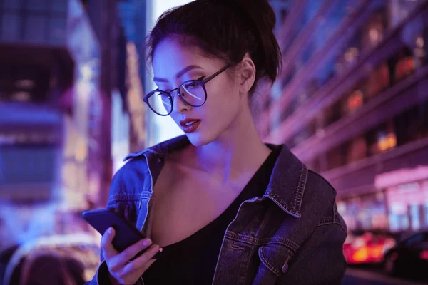 Kobieta za pomocą smartfona w mieście nocą — Zdjęcie stockowe
