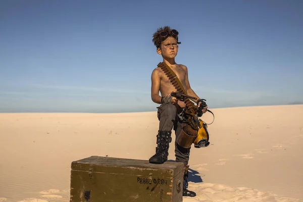 Post-apocalyptic boy outdoors in desert.