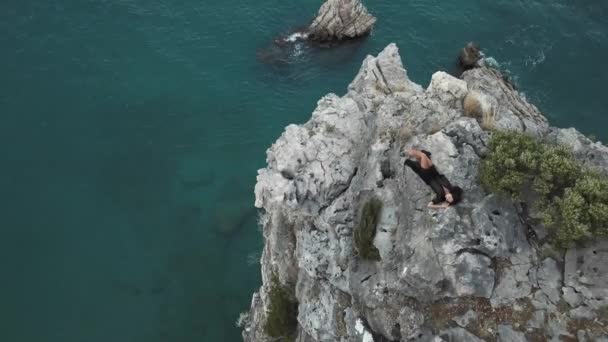 Luftaufnahme einer jungen Frau auf einer Felswand gegen das Meer — Stockvideo