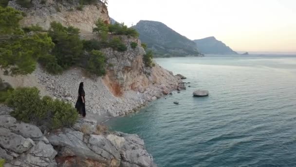 Luftaufnahme einer jungen Frau auf einer Felswand gegen das Meer — Stockvideo