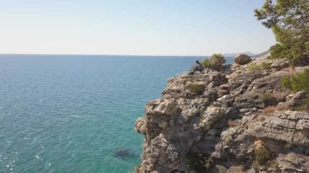 Vue Aérienne Du Jeune Homme Voyageur Sur Une Falaise Rocheuse Contre La Mer. — Video