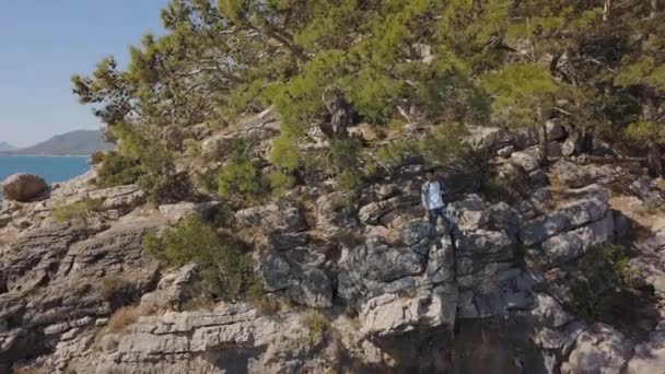 Veduta aerea del giovane viaggiatore sulla scogliera rocciosa contro il mare. — Video Stock