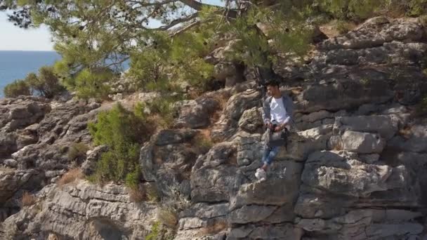 Vue Aérienne Du Jeune Homme Voyageur Sur Une Falaise Rocheuse Contre La Mer. — Video