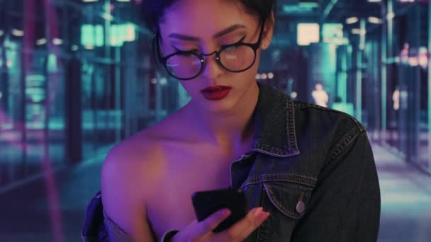 Mujer usando un teléfono inteligente en la ciudad por la noche — Vídeos de Stock