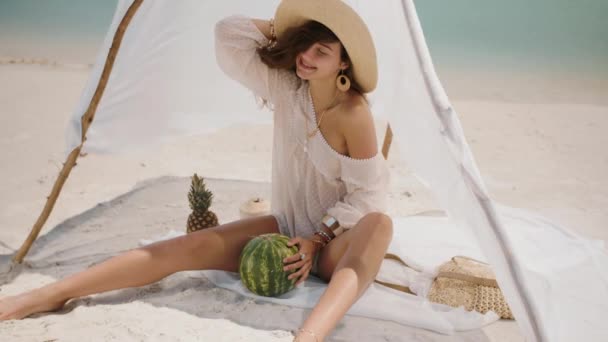 Женщина на тропическом пляже ест арбуз — стоковое видео