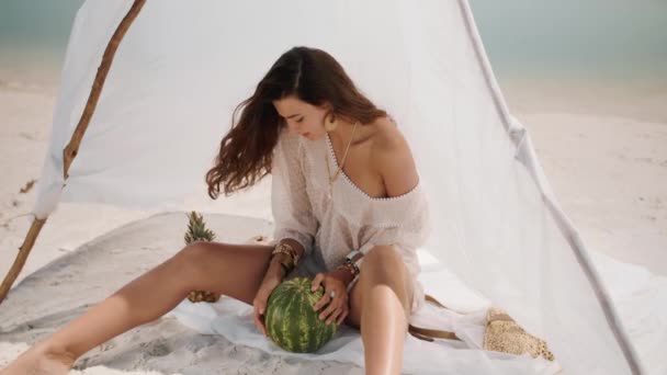 Женщина на тропическом пляже ест арбуз — стоковое видео