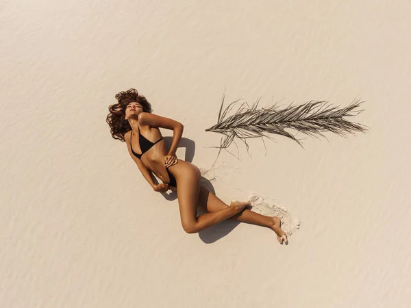 Luftaufnahme einer Frau im Badeanzug-Bikini, die sich entspannt und am Strand sonnt — Stockfoto