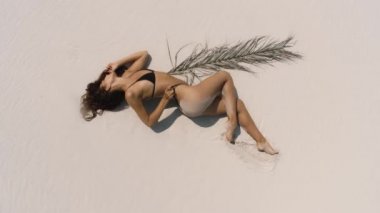 Bikini mayo giymiş, kumsalda güneşlenen bir kadının en iyi hava aracı görüntüsü.