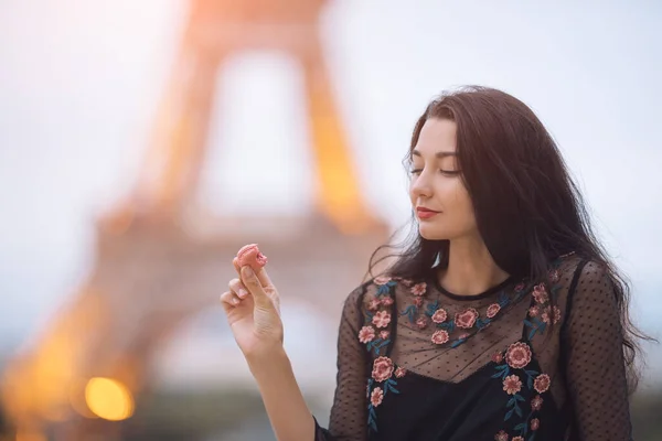 Párizsi nő mosolyog eszik a francia tészta makaron Párizsban ellen Eiffel torony. — Stock Fotó