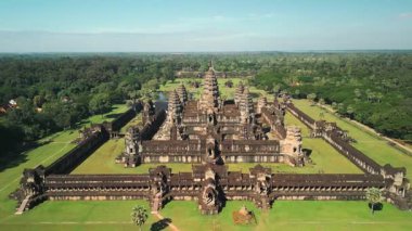 Kamboçya 'daki Angkor Wat Tapınağı kompleksinin yemyeşil ormanlarla çevrili dinamik havadan uçuş görüntüleri. Seyahat tanıtımları, kültürel belgeseller, turizm reklamları ve miras kavramları için mükemmel..