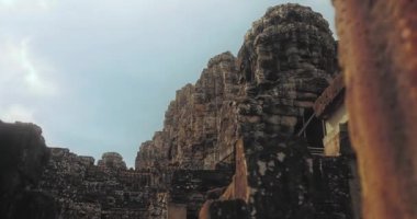 Sorunsuz hareket eden video kamera, Angkor Thom, Kamboçya 'daki Bayon tapınağı taş yüz kulelerinin detaylı görüntülerini çeker. İkonik Khmer mistik atmosferiyle harabe halinde. Miras, tarih ve turizm konsepti.